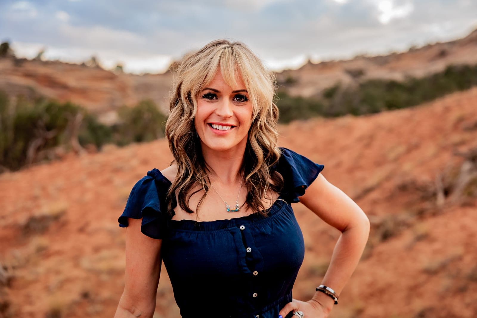 Alisa Sampson smiling outdoors in a navy top against red Utah desert terrain