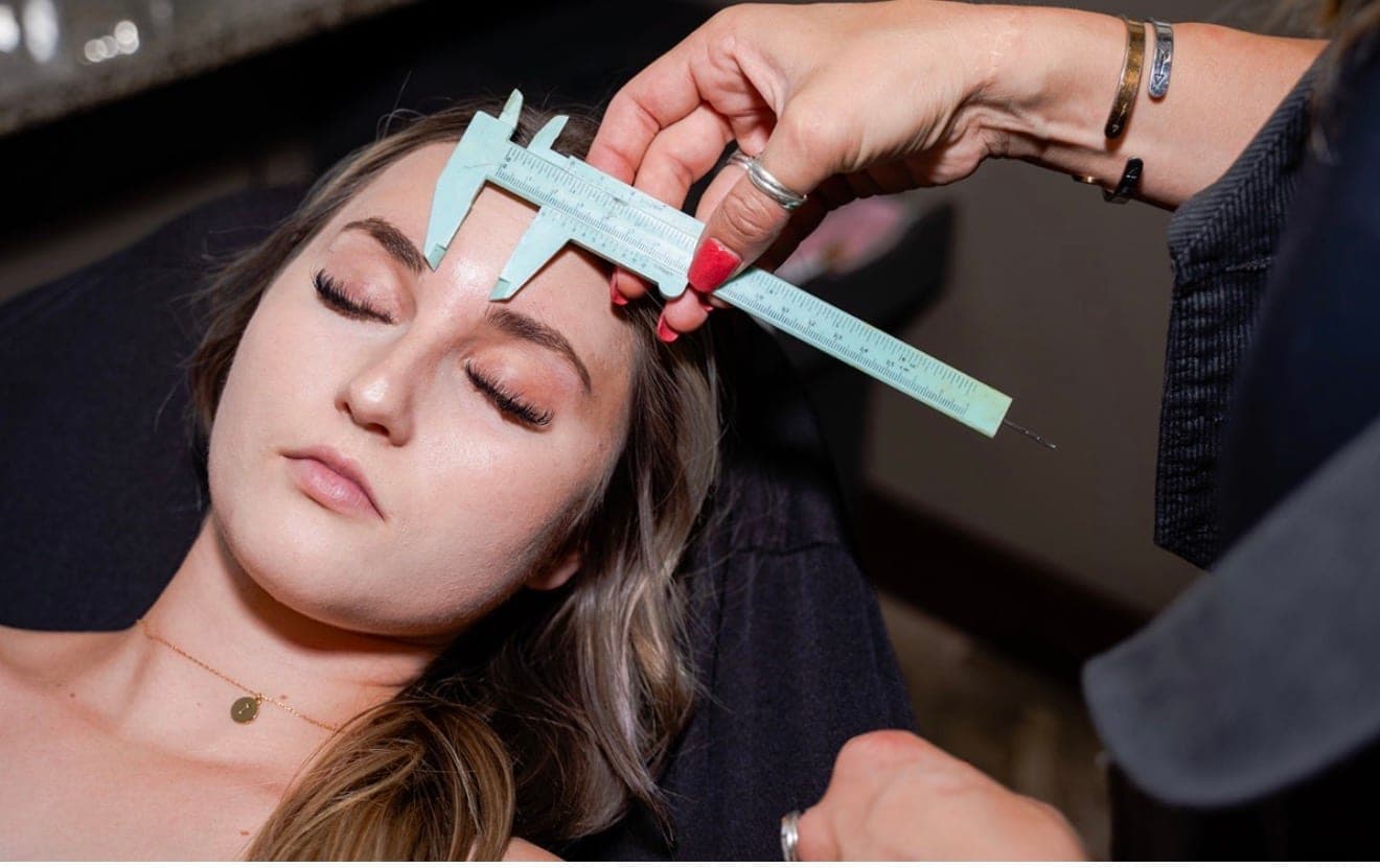 Alisa mapping a client's brows with a precision caliper