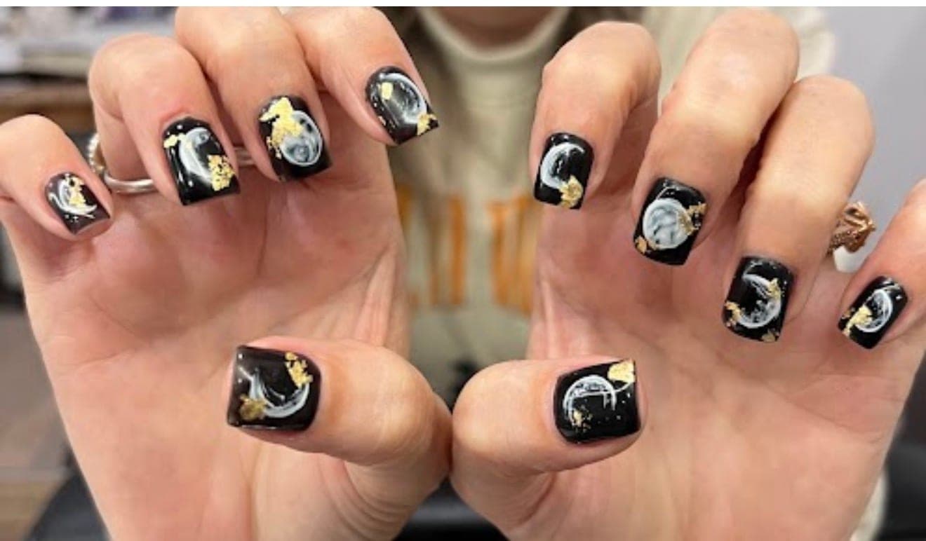 Glossy black nails with white smoke and gold-leaf accents